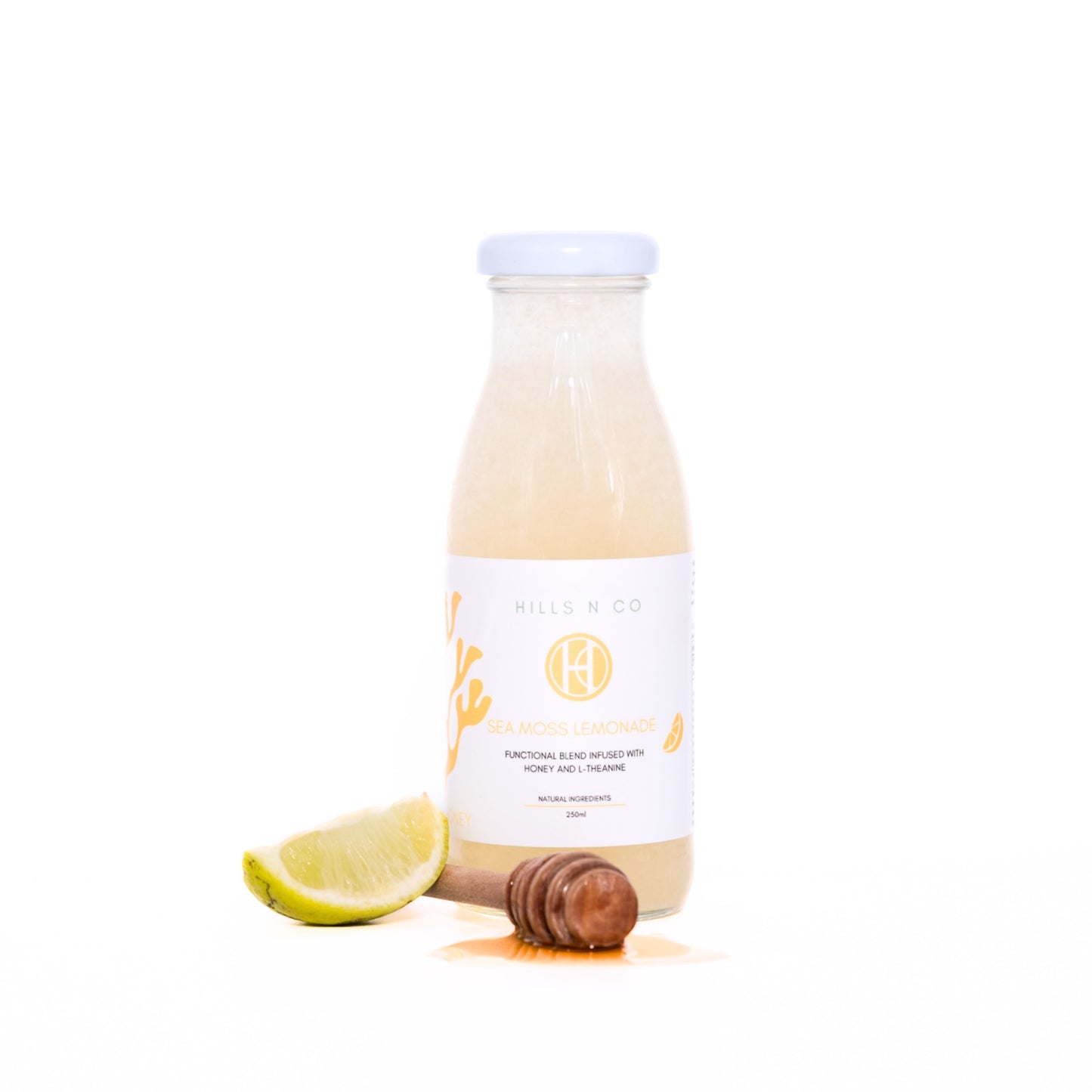 Hills N Co Honey Sea Moss Lemonade bottle with lime wedge and honey dipper. Supports skin and gut health.