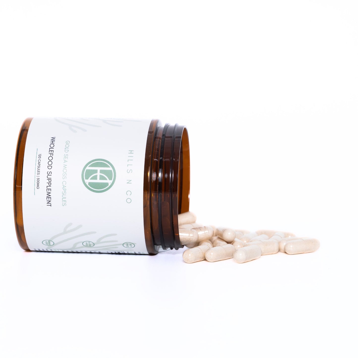 Hills N Co Gold Sea Moss Capsules supplement bottle tipped over with capsules spilling out.